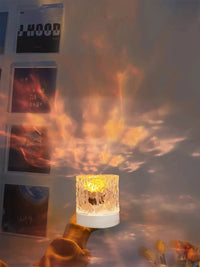 Lampe cristal ondulation d'eau – lampe cristal en main devant un mur de cadres