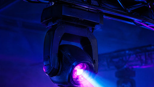 Lyre LED projetant un faisceau rose et bleu sous un pont de scène