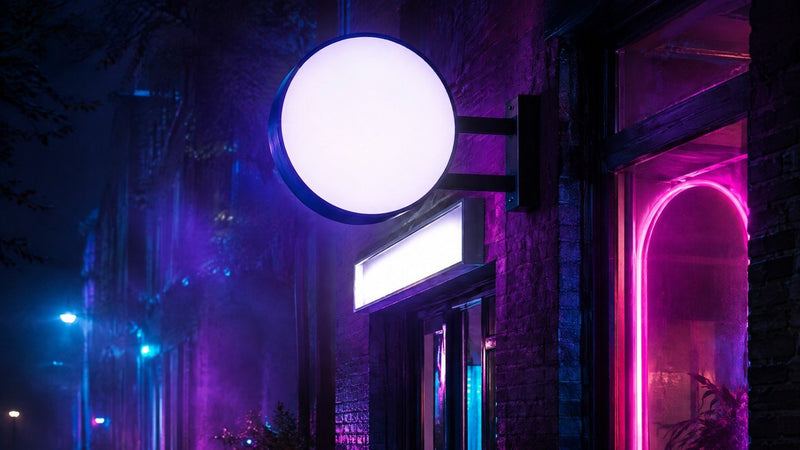 Enseigne drapeau lumineuse ronde et néon rose en vitrine d'une boutique, la nuit